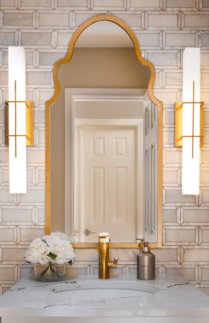 Whether its those eye-cataching lights, brass framed mirror, or the peril tiles, this is a stunning powder room